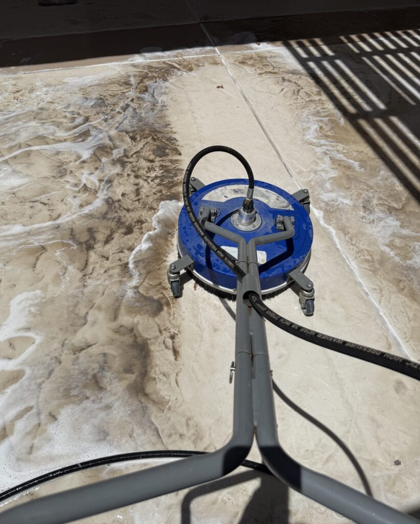 Pressure washer cleaning a stained patio or pool deck in Las Vegas and Henderson, showing a dramatic difference between dirty and clean concrete.