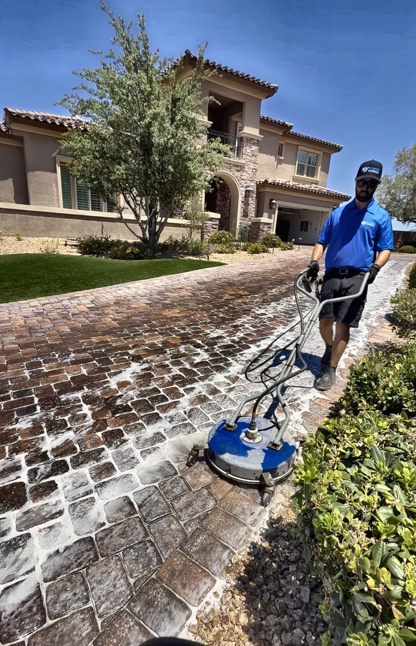 NV Power Washing technician in branded uniform cleaning a paver driveway with a professional surface cleaner in Henderson, NV